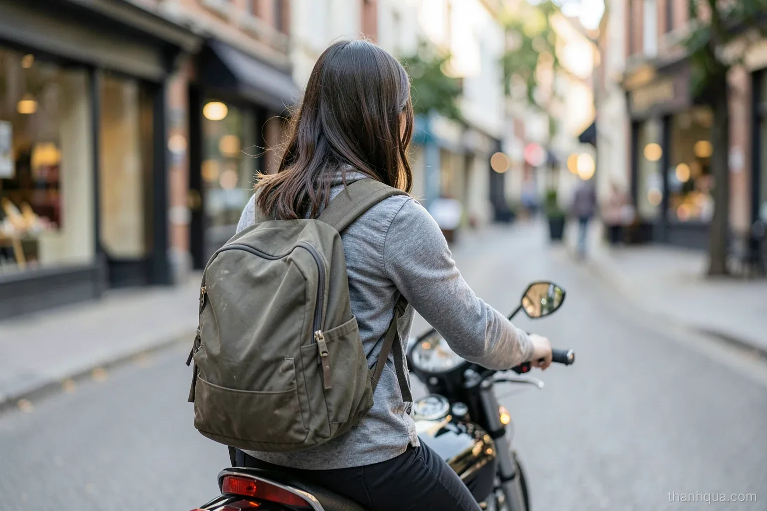 A young woman seen from behind riding a motorbike on a quiet Saturday morning street, a backpack strapped on, soft early light and blurred shopfronts